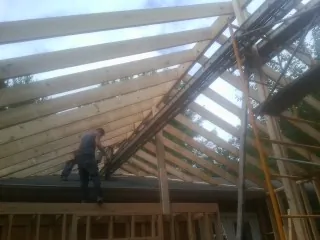 Rafters going up over a new addition with a worker on the wall in Erie